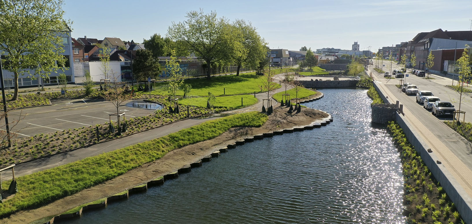 Nyanlagt kanal og bynært parkområde med grøn skråning, stiforløb og nyplantede træer.