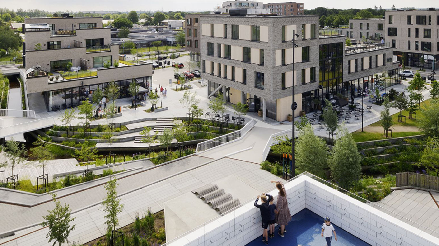 Luftfoto af bytorv med beplantede regnvandsbede, terrasseret grønt anlæg og ny bebyggelse.
