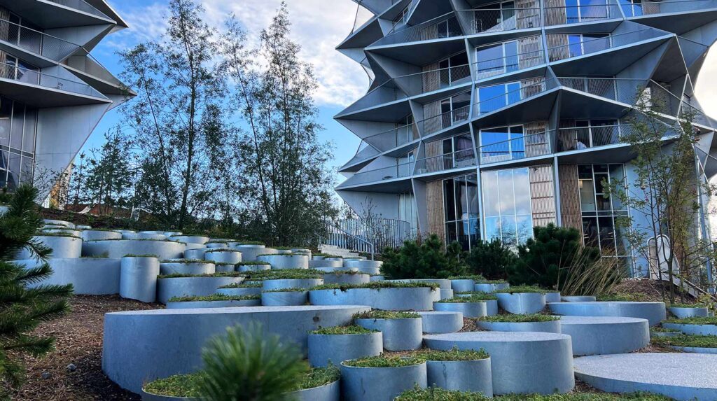 Cylinderformede betonplantekummer i varierende højder skaber et grønt terrasseanlæg ved boligbebyggelsen Kaktustårnene.