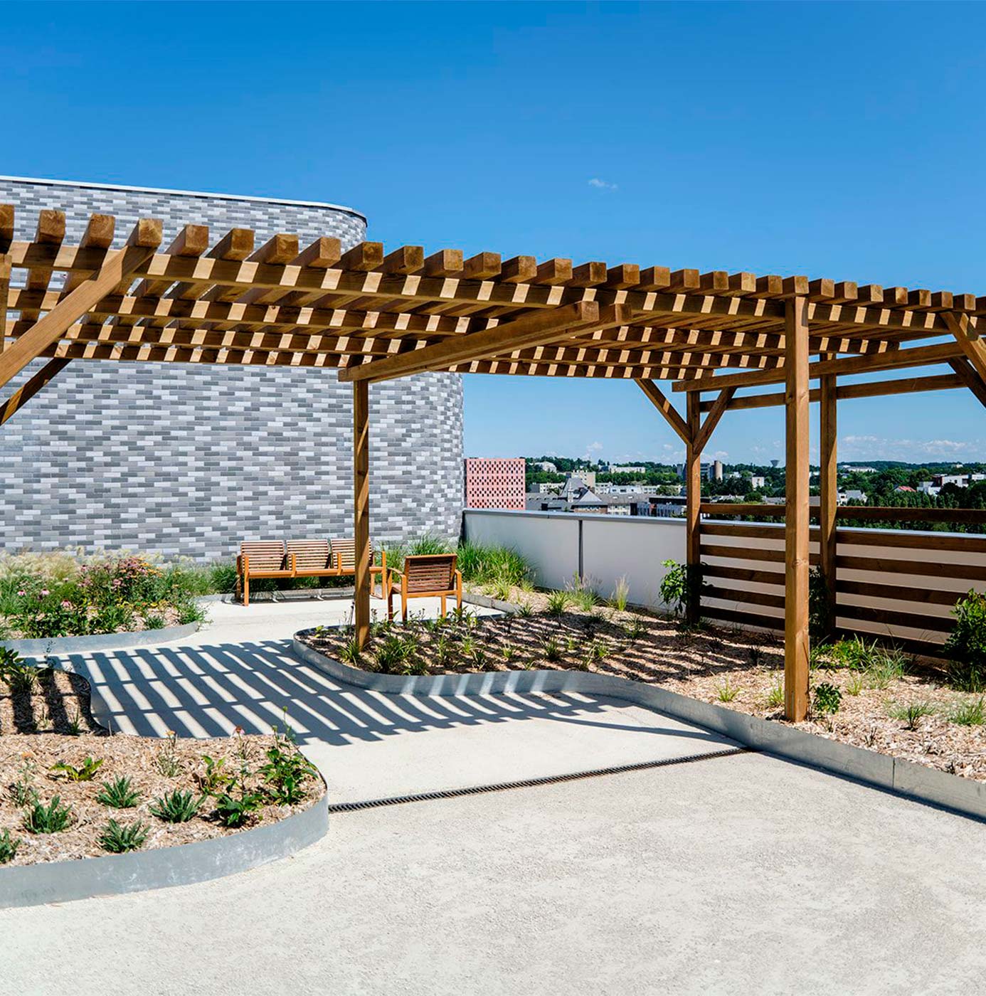 Anlagt tagterrasse med træpergola, siddeområde og bede med stauder og buske.